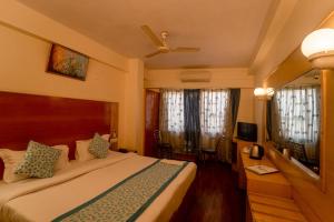 Vatika Inn Hotel City Center في أودايبور: غرفة نوم بسرير ومكتب ونوافذ