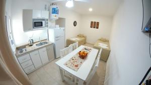 una pequeña cocina blanca con mesa y una pequeña cocina con fregadero en SUEÑOS DE TERMAS en Chajarí