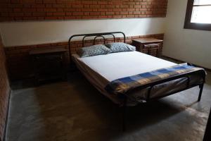 a bed in a room with a brick wall at Casa em Condomínio Estrada de São Roque Estrada do Vinho in São Roque