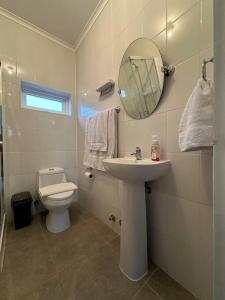 a bathroom with a toilet and a sink and a mirror at Tú Casa en Puerto Natales in Puerto Natales