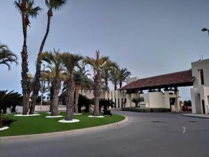 um parque de estacionamento com palmeiras em frente a um edifício em Villa Roda Golf and Beach Resort,3 bedrooms, private, heated swimming pool, garden, parking space em Múrcia