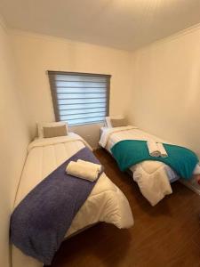 two twin beds in a room with a window at Tú Casa en Puerto Natales in Puerto Natales