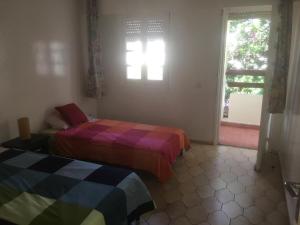 two beds in a room with a window and a window at DUPLEX VILLA RESIDENCE LA CORNICHE juste à coté de la plage in Mohammedia