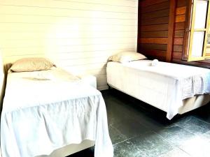 two beds in a room with white sheets at Pousada Casa da Noiva in Guarulhos