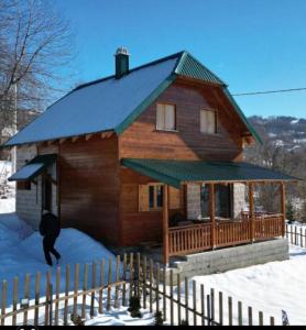 a log cabin with a man walking in the snow at Apartment Dulovine in Kolašin