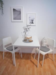 nette 1 Zimmerwohnung in Würzburg في فورتسبورغ: طاولة غرفة طعام بيضاء و كرسيين مع إناء من الزهور