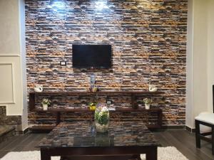 a living room with a stone wall with a tv at YOUVALA Serviced Apartment 2nd District in 6th Of October