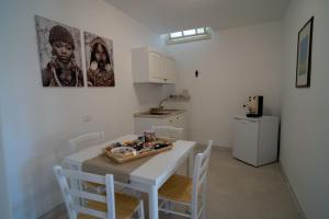 een keuken met een witte tafel en witte stoelen bij Lamapulia in Torre a Mare