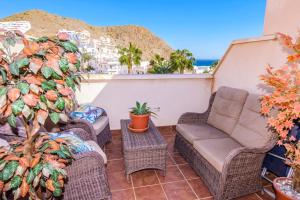 un patio con sillas de mimbre y un sofá en el balcón en Beach House Millares, en Carboneras