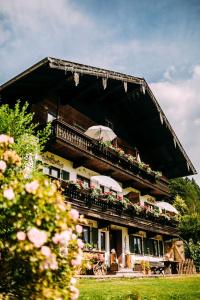 um edifício com uma varanda com flores e um guarda-chuva em Dandl-Hof em Ruhpolding