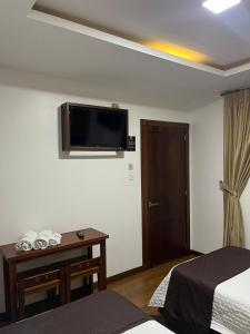 una camera d'albergo con due letti e una televisione a parete di HOSTAL CAMIL a Loja