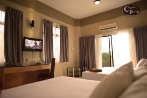 a hotel room with a bed and a tv and a bed at City Times Hotel in Kuantan