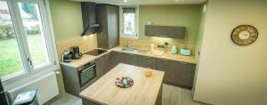 a kitchen with a wooden table and a clock on the wall at Gîte l'escapade 90 in Rougegoutte