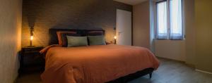 um quarto com uma cama com um cobertor laranja e uma janela em Gîte l'escapade 90 em Rougegoutte