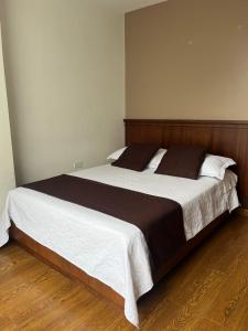 a bedroom with a large bed with a wooden headboard at HOSTAL CAMIL in Loja