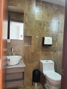 y baño con aseo y lavamanos. en HOSTAL CAMIL, en Loja