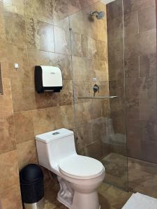 a bathroom with a toilet and a glass shower at HOSTAL CAMIL in Loja
