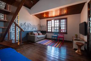 a living room with a staircase and a couch and a tv at Hostel LARes in Brumadinho