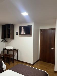 Habitación con cama, mesa y TV. en HOSTAL CAMIL, en Loja
