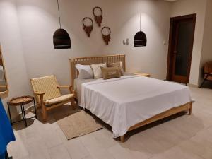 a bedroom with a large bed and a chair at Serenity Terraces Beach, Hotel - Kokrobite in Kokrobite