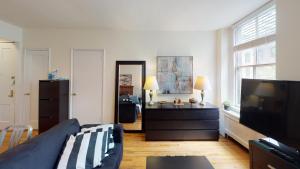 Cozy place in midtown NYC في نيويورك: غرفة معيشة مع أريكة وتلفزيون بشاشة مسطحة