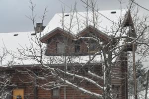 domek z bali i śniegiem na dachu w obiekcie Oreias Chalet w mieście Ano Trikala