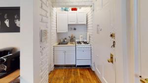 a white kitchen with a sink and a stove at Cozy place in midtown NYC in New York