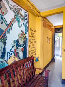 eine Holzbank vor einer Wand mit Wandmalereien in der Unterkunft Hotel San Francisco in San Pedro La Laguna