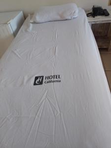 uma cama branca com um logótipo de hotel da Califórnia em Hotel California em Goiânia