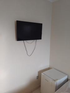 uma televisão de ecrã plano pendurada numa parede branca em Hotel California em Goiânia