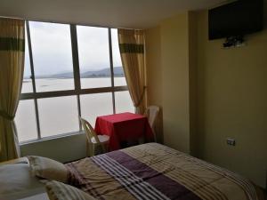 um quarto com uma cama, uma mesa e uma janela em Hotel Angostura em Cochabamba