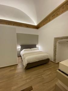 een witte slaapkamer met een bed en houten vloeren bij Duomo Holiday in Napels