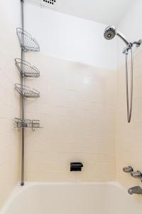 a shower in a bathroom with a white tile wall at Apartment 1411: Fort Greene in Brooklyn