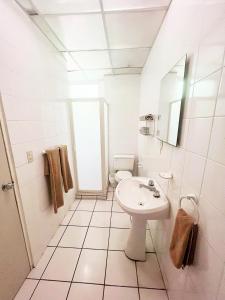 La salle de bains blanche est pourvue d'un lavabo et de toilettes. dans l'établissement Suites Galván centro Colima, alberca, Wifi, parking, à Colima