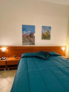 a bedroom with a blue bed and three pictures on the wall at Hotel Vico Alto Siena in Siena