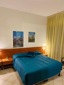 a bedroom with a bed with a blue blanket at Hotel Vico Alto Siena in Siena
