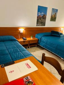 una camera d'albergo con due letti e un tavolo di Hotel Vico Alto Siena a Siena