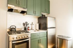 ニューヨークにあるApartment 235: Lower East Sideのキッチン(緑のキャビネット、ステンレス製の冷蔵庫付)