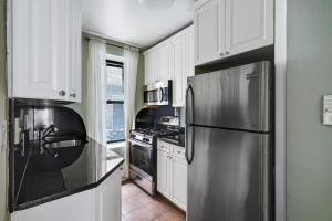 La cuisine est équipée d'un réfrigérateur en acier inoxydable et de placards blancs. dans l'établissement Apartment 549: Upper West Side, à New York