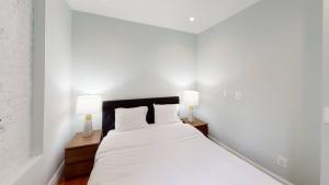 a white bedroom with a large bed with two lamps at Apartment 494: East Village in New York