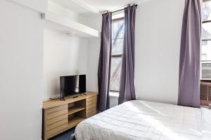 1 dormitorio con 1 cama, TV y ventana en Apartment 1407: East Village en Nueva York