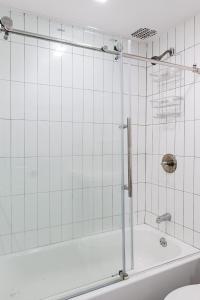 een douche in een badkamer met witte tegels bij Apartment 1407: East Village in New York