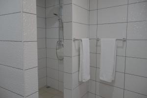 La salle de bains est pourvue de murs carrelés blancs et de serviettes blanches. dans l'établissement Village Center One Bedroom Apartment, à Porto Moniz