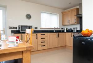 a kitchen with a wooden table and a black refrigerator at Picton Lodge in Holywell