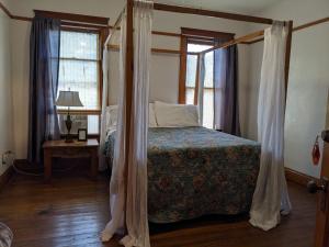 a bedroom with a canopy bed and two windows at The Oliver House in Bisbee
