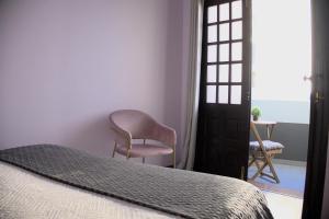1 dormitorio con silla, cama y ventana en Village Center One Bedroom Apartment, en Porto Moniz