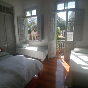 a bedroom with two beds and two windows at Pousada Gameleira in Diamantina