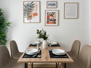 einen Esstisch mit Stühlen und einen Holztisch mit Tellern in der Unterkunft Picú Home - Nueva apertura in Málaga