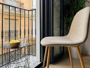 una silla y una mesa frente a un balcón en Picú Home - Nueva apertura en Málaga