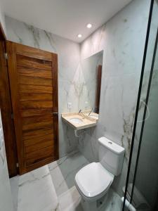 La salle de bains est pourvue de toilettes, d'un lavabo et d'une porte en bois. dans l'établissement Pousada Amoré em Porto de Galinhas, PE, à Porto de Galinhas